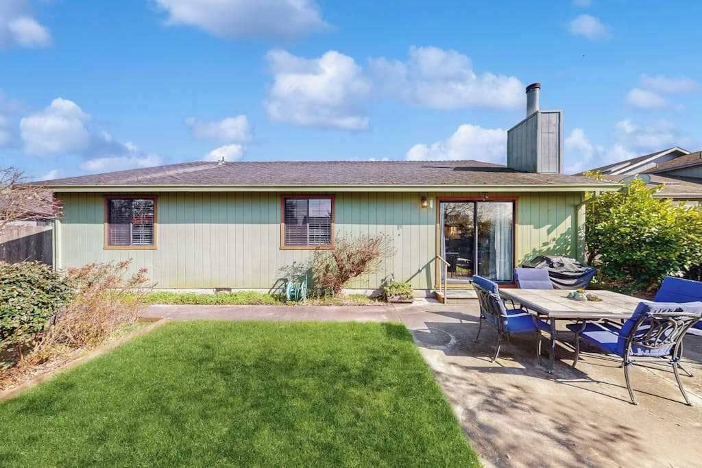 A single-story house with a front door, a small front yard, and a patio area with a table and chairs.