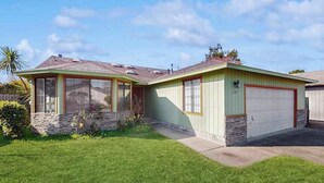 Ein eingeschossiges Haus mit Garage, einer Veranda und einem gepflegten Rasen.