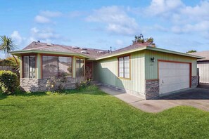 Ein eingeschossiges Haus mit Garage, einer Veranda und einem gepflegten Rasen.