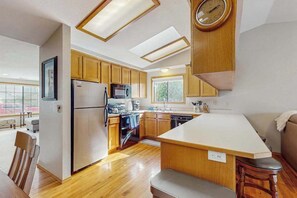 Eine moderne Küche mit Holzschränken, einer zentralen Kochinsel, einem eingebauten Backofen und einer Mikrowelle.