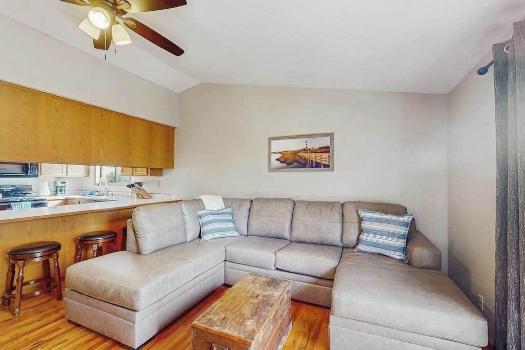 Ein Wohnzimmer mit einer Eckcouch, einem Couchtisch aus Holz und einem Deckenventilator.