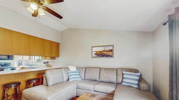 Ein Wohnzimmer mit einer Eckcouch, einem Couchtisch aus Holz und einem Deckenventilator.