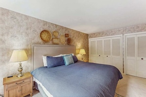 Ein Schlafzimmer mit einem Bett, Nachttischlampen, einem Nachttisch, einem Kleiderschrank und Wanddekoration.