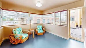 A room with two wicker chairs, a small table, and a floor lamp. - Eureka Theater Apartment (Eureka)