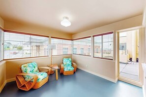 Ein Zimmer mit zwei Korbstühlen, einem kleinen Tisch und einer Stehlampe.