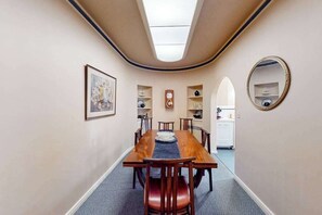 A dining area with a long wooden table, chairs, a clock, and a mirror on the wall. - Eureka Theater Apartment (Eureka)