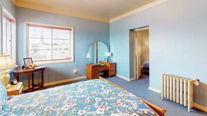 A bedroom with a bed, dresser, mirror, window, and radiator. - Eureka Theater Apartment (Eureka)