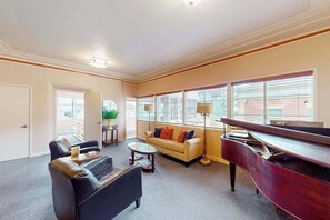 Ein Wohnzimmer mit Klavier, Sofa, Couchtisch und Blick durch große Fenster.