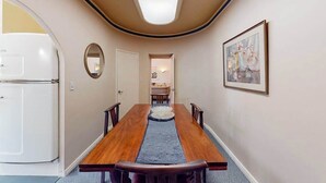 A narrow hallway with a wooden dining table, chairs, a mirror, and a framed picture on the wall. - Eureka Theater Apartment (Eureka)