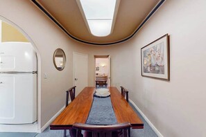 Ein schmaler Flur mit einem Holztisch, Stühlen, einem Spiegel und einem gerahmten Bild an der Wand.
