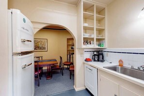 A compact kitchen with a refrigerator, a coffee maker, and a sink. - Eureka Theater Apartment (Eureka)
