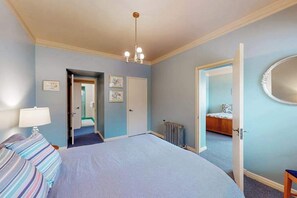 A bedroom with a bed, a radiator, a door leading to another room, and a chandelier. - Eureka Theater Apartment (Eureka)