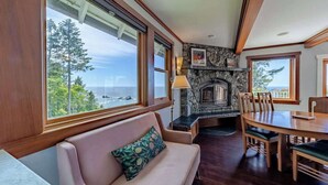 A room with a fireplace, a dining table, and a sofa. - The Trinidad Pearl - Oceanfront Home & Hot Tub (Trinidad)