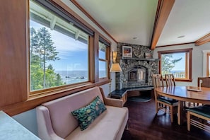 A room with a fireplace, a dining table, and a sofa. - The Trinidad Pearl - Oceanfront Home & Hot Tub (Trinidad)
