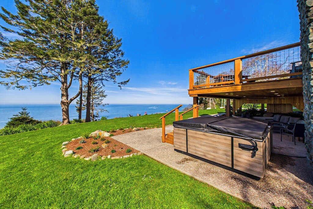 A modern outdoor kitchen area with a built-in grill, a wooden deck, and a stone wall.