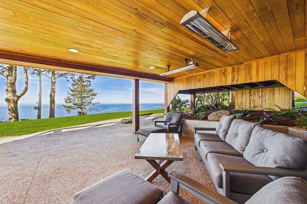 Een terras met uitzicht op de oceaan, een houten plafond en een tafel.