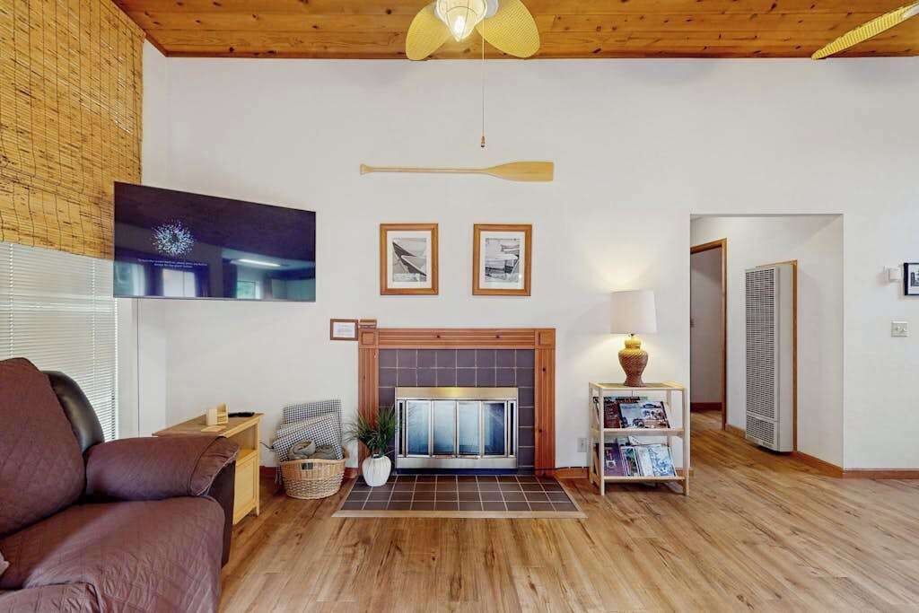 A living room with a fireplace, a television mounted on the wall, and a wooden ceiling.