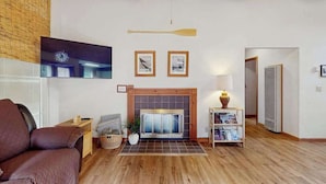A living room with a fireplace, a television mounted on the wall, and a wooden ceiling. - Arcata Townhouse - Modern Downtown Coastal Getaway (Arcata)