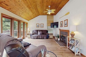 Amplia sala de estar con techo de madera, chimenea y sofá.