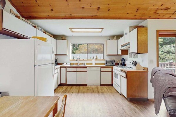 A compact kitchen with white cabinets, a central island, and a window overlooking a natural landscape.