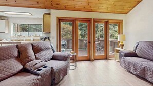 Una habitación con techo de madera, una puerta corrediza de vidrio que da a una terraza exterior y dos sofás.