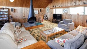 A cozy living room with a fireplace, sofas, a coffee table, and a television. - Ocean Treasures - Charming Coastal Home Near the Beach (Smith River)