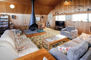 A cozy living room with a fireplace, sofas, a coffee table, and a television. - Ocean Treasures - Charming Coastal Home Near the Beach (Smith River)