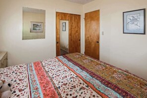 Een slaapkamer met een bed, een kaptafel, een spiegel en twee deuren.
