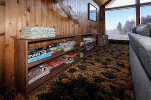 Een gezellige kamer met houten wanden, een groot raam en een boekenplank vol puzzels.