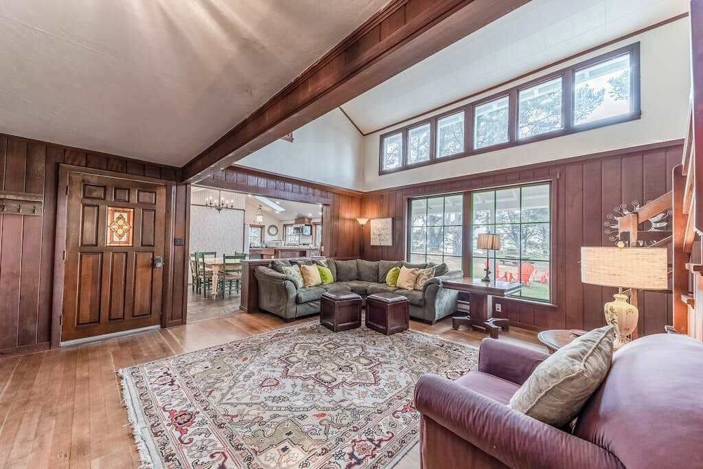 A spacious living room with a large sectional sofa, a patterned rug, and a dining area visible through an open door.