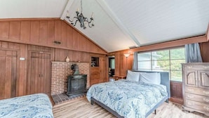 Een slaapkamer met een bed, een dressoir, een open haard en een raam.