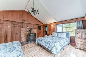 A bedroom with a bed, a dresser, a fireplace, and a window. - Seaside Meadow - Peaceful Coastal Retreat Surrounded by Nature (Trinidad)