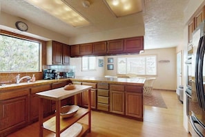 A kitchen with wooden cabinets, a central island, and a refrigerator. - Humboldt Bay Retreat (Eureka)