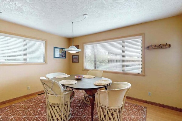 A dining area with a round table, six chairs, and a ceiling light fixture. - Humboldt Bay Retreat (Eureka)