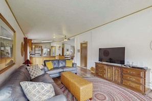 A living room with a sofa, ottoman, TV, and wooden cabinet. - Pacific View Escape - Bay Views & Jetted Tub (Loleta)