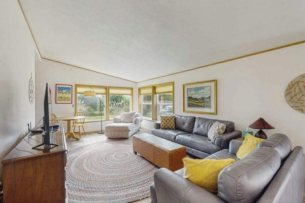 A living room with a sofa, ottoman, and a television on a wooden stand.