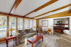 A living room with a sofa, coffee table, and a painting on the wall. - Redwood Coast River House (Crescent City)