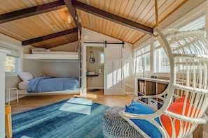 A cozy bedroom with a bunk bed, a hanging chair, and a large window providing natural light. - Seagull's Bluff - Scenic Coastal Retreat with Ocean Views (Trinidad)