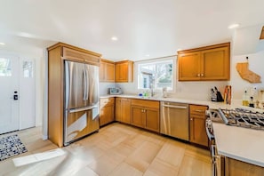 A modern kitchen with stainless steel appliances, wooden cabinets, and a large window providing natural light. - Seagull's Bluff - Scenic Coastal Retreat with Ocean Views (Trinidad)