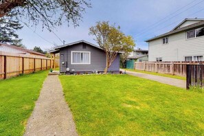 A residential property with a paved driveway, a grassy yard, and a wooden fence. - Cedar Street Cottage (Eureka)