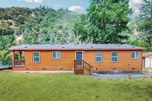 A two-story wooden house with a porch, a front door, and a small staircase leading to the entrance. - Trinity River Retreat (Willow Creek)