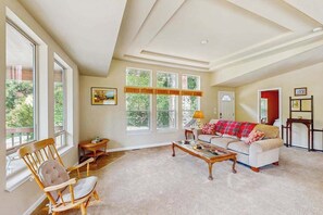 A spacious living room with a high ceiling, large windows, a sofa, a coffee table, and a chair. - Trinity River Retreat (Willow Creek)