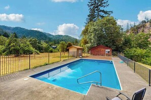 A rectangular swimming pool with a metal ladder, surrounded by a concrete deck. - Trinity River Retreat (Willow Creek)