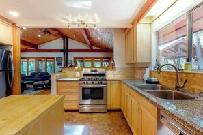 A modern kitchen with wooden cabinetry, stainless steel appliances, and a large window providing natural light.