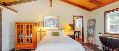 Ein Schlafzimmer mit einem großen Bett, einem Holzkopfstück, einem Schrank, einem Schreibtisch und einem Fenster.