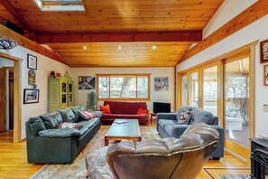 A spacious living room with wooden beams, a green cabinet, and a red sofa.