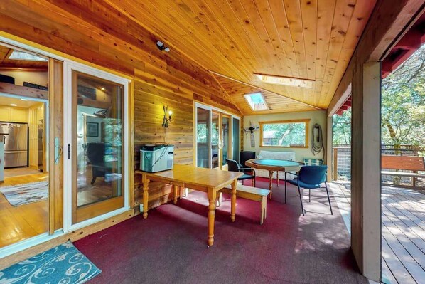 A wooden interior with a dining area, a kitchen, and a view of the outdoors.
