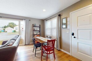 Un coin repas comprenant une table et des chaises, un canapé et une porte dotée d’un miroir.
