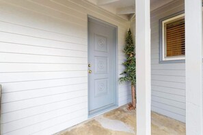 A house with a grey door, a small Christmas tree, and a window with blinds. - Dean Getaway - Peaceful Coastal Escape for the Whole Family (Eureka)