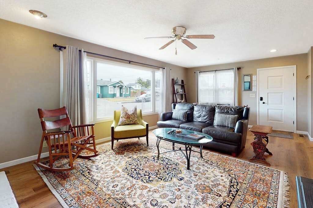 A living room with a sofa, armchairs, a coffee table, and a patterned rug.
